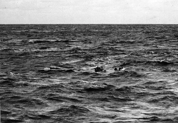 A U-boat sinks quickly and members of her crew, some in rubber dinghies, others swimming