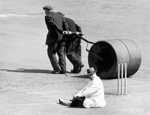 Umpire taking a rest whilst groundsmen roll the wicket. 15th July 1952