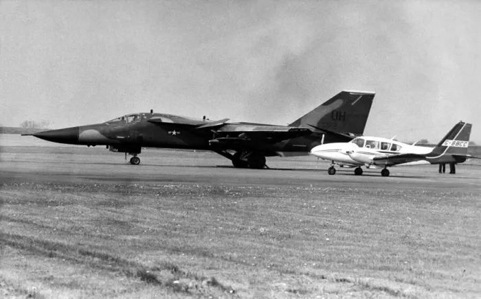 Framed Print : A USAF General Dynamics F-111 Aardvark sits on an airfield next to twin engined civil Framed Print : A USAF General Dynamics F-111 Aardvark sits on an airfield next to twin engined civil