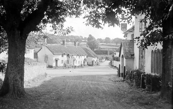 View of a street in the village of Broadhenbury in Devon showing thatched roof cottages
