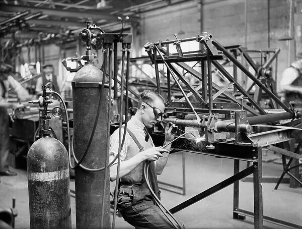 A welder constructs the fuselage framework of the Miles 3 Falcon aircraft at the Philips