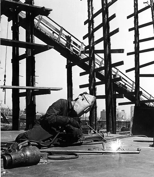 A welder puts together sectons of a ship in the Scottish shipyard Circa 1955