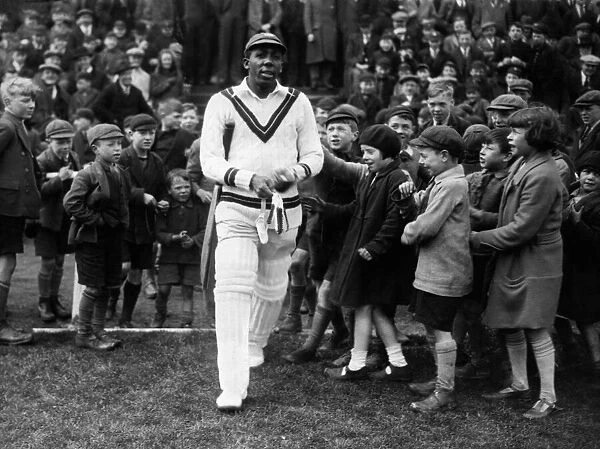 West Indies cricketer Learie Constantine walks out on to the field past excited children