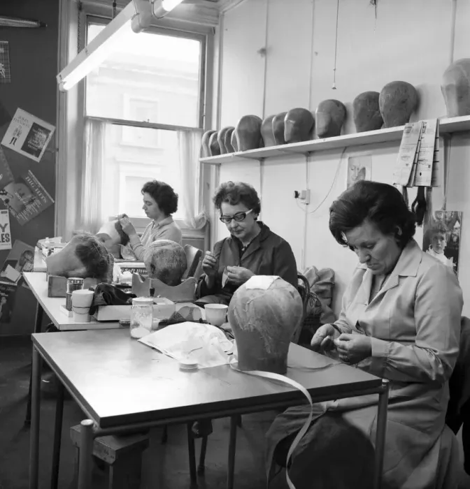 Framed Print : Wigmakers Workshop: Women making wigs whilst in another part of the workshop hair is Framed Print : Wigmakers Workshop: Women making wigs whilst in another part of the workshop hair is