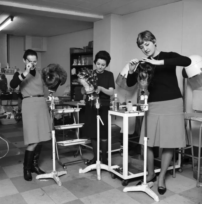 Framed Print : Wigmakers Workshop: Women making wigs whilst in another part of the workshop hair is