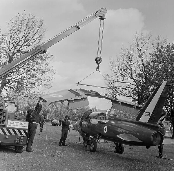 The wings being attached to a Folland Gnat of the Red Arrows in preparation for a Royal