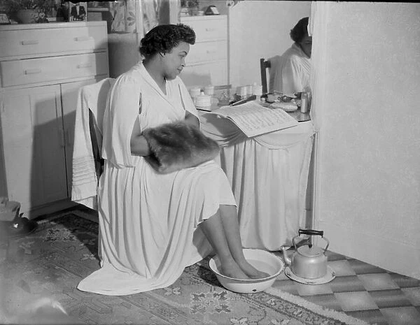 Winifred Atwell, pianist, puts her feet into bowl of hot water