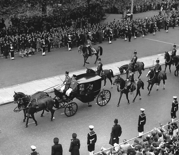 Winston Churchill gives his two finger salute to the crowds from the lead carriage of
