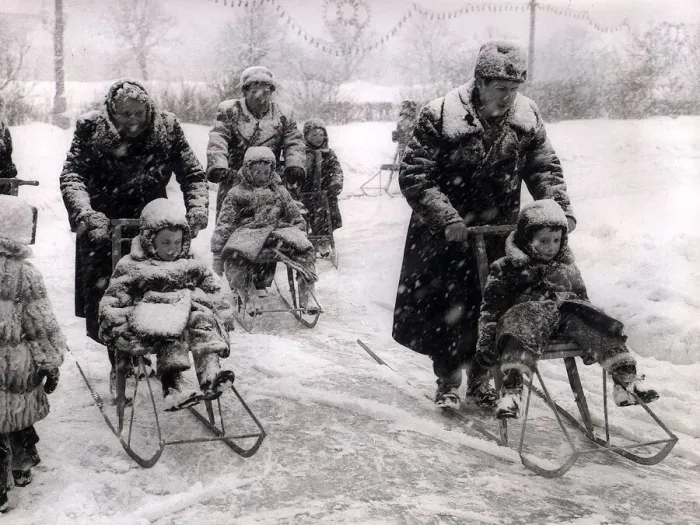 Framed Print : Winter Russian style with adults pushing children in chair sledges while being well