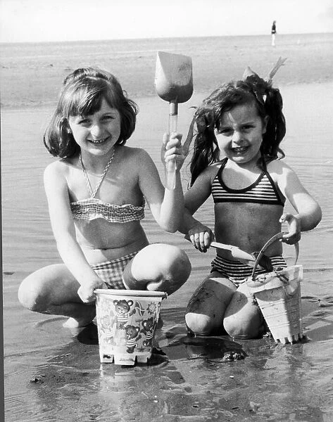 Wish you were here! Sharon-Anne Taney, left, and Maria Grant build a sand castle in