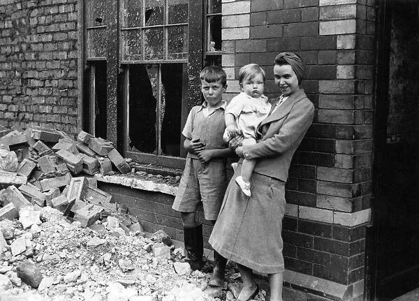A woman and children standing amongst the rubble outside a building in South Wales