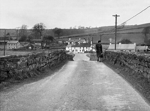 A woman crossing the bridge the village of Llangendeirne in the River Gwendraeth river
