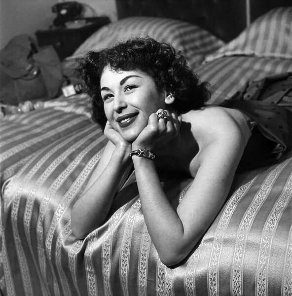 Woman in dress posing on bed. March 1952 C1581-002