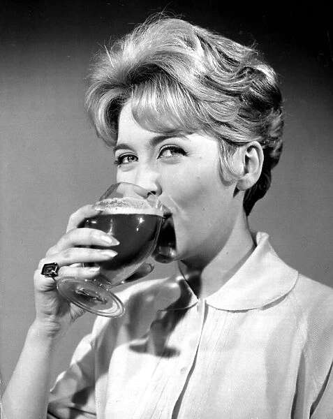 Woman drinking from cocktail glass November 1961