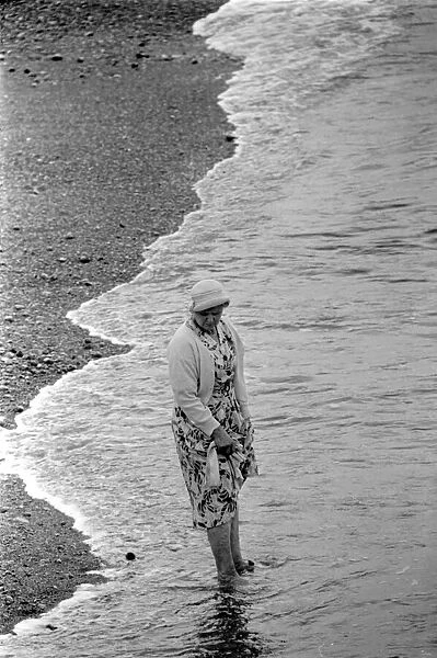 A woman goes for a paddle in the sea on the beach at Brighton July 1958