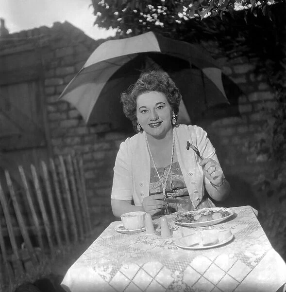 Woman having picnic in the rain. July 1953 D3603