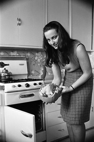 A woman in a kitchen cooking a chicken with a Bobo Pot. 29th March 1967