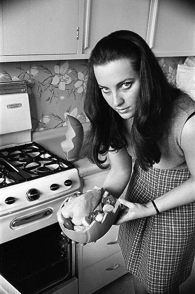 A woman in a kitchen cooking a chicken with a Bobo Pot. 29th March 1967