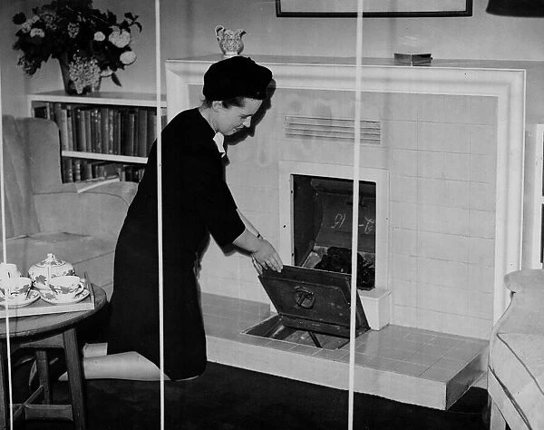 A woman kneels down to clean her continuous burning coal fire May 1945