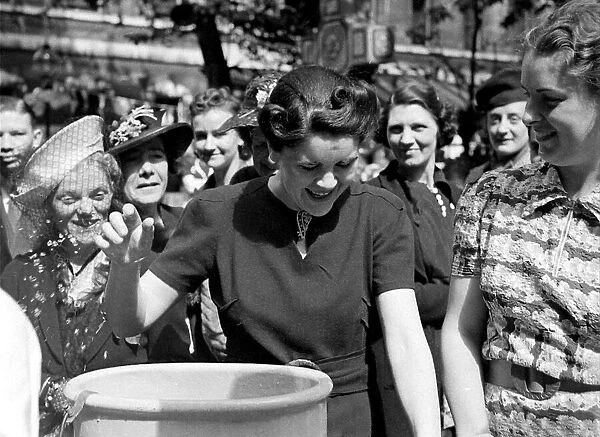 A woman laughs as she dunks her hands into a bucket at Barts Fair circa 1938
