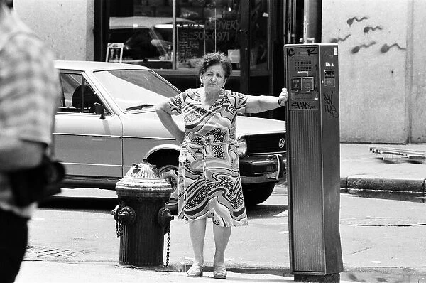 Woman leans against Street Fire Alarm Box, used to report an emergency, New York, USA