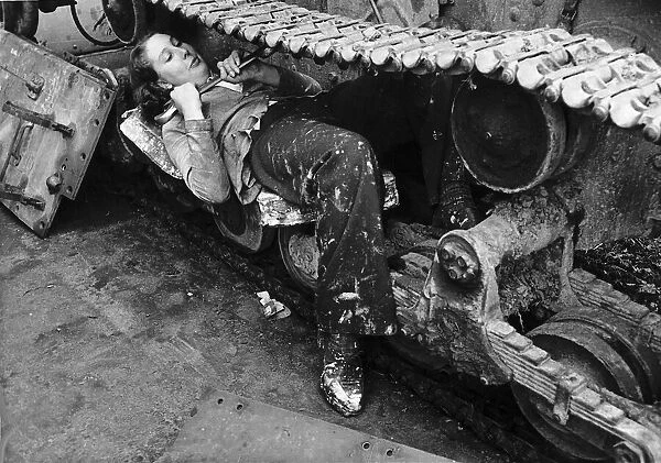 A woman in a Ministry of Supply munitions depot works on the catapillar track of a tank