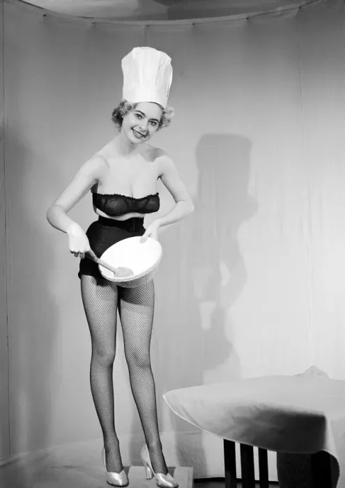 Framed Print : Woman modelling black lingerie and a chefs hat in a cooking photo shoot. Circa 1964