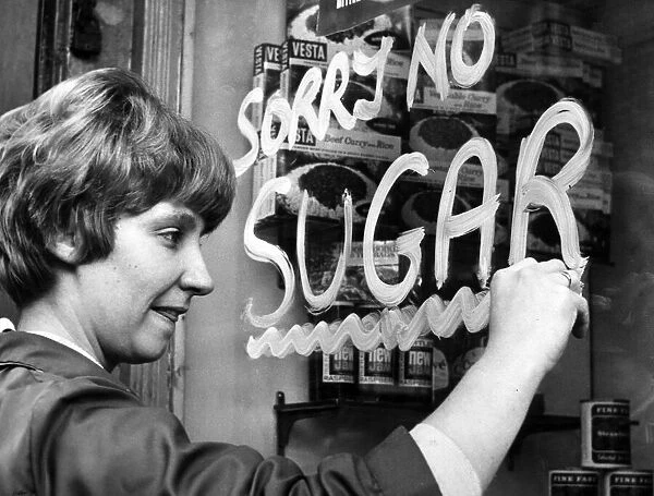 A woman paints a Sorry No Sugar sign on a shop window in Liverpool