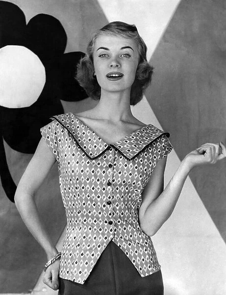 Woman poses wearing sleveless patterned blouse with large collar. July 1955 P012657