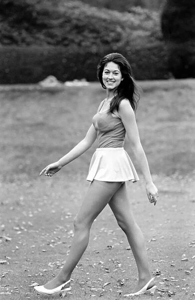 Woman posing outdoors wearing a short white skirt and vest top