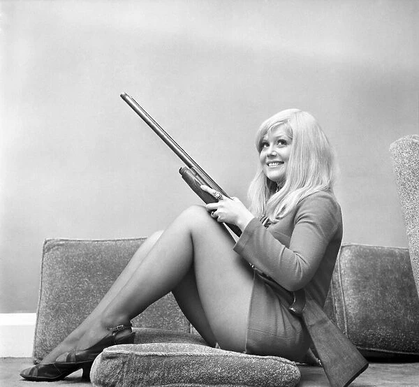 A woman posing wearing a mini dress and holding a shot gun November 1969