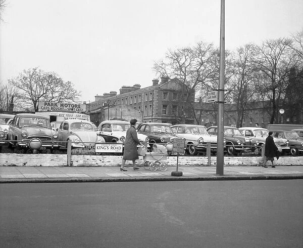 A woman and a pram pass a deserted second hand car lot in the Kings Road Chelsea