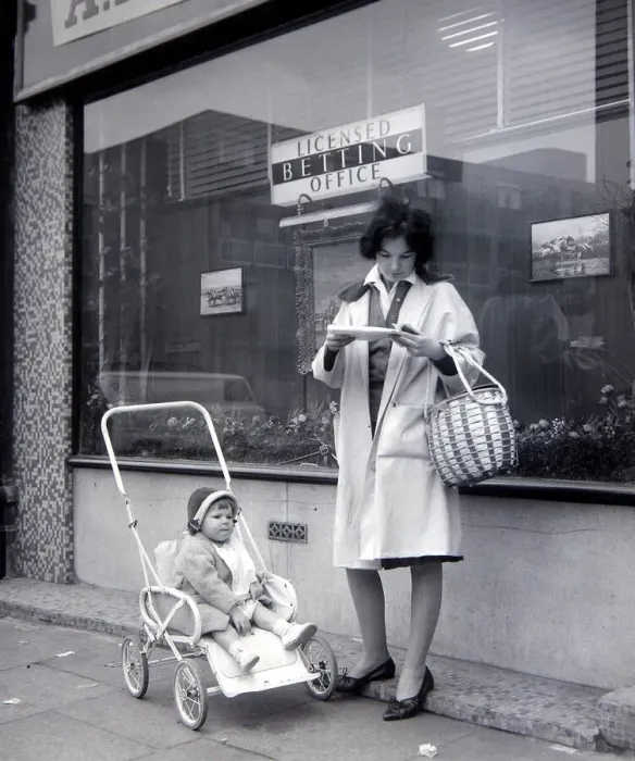 Framed Print : A woman punter studies the form guide outside A E Fane and Co betting shop in islington Framed Print : A woman punter studies the form guide outside A E Fane and Co betting shop in islington