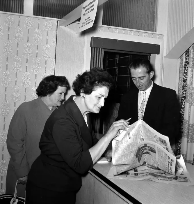 Framed Print : A woman punter studying the form guide before placing a bet in a betting shop