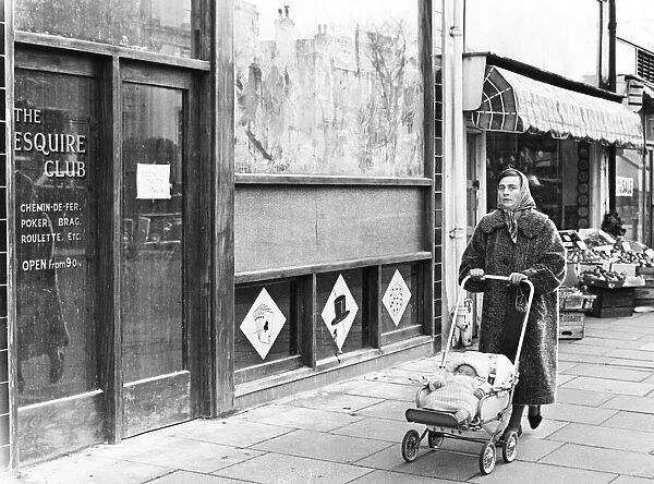 Woman pushing her baby in a pram along a Swansea street. 1st January 1965