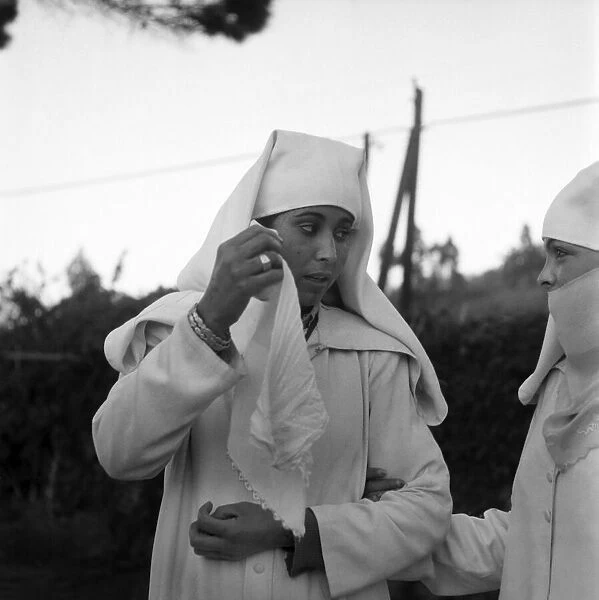 Woman putting on a Djellabah traditional dress. January 1953 D216-014 *** Local Caption
