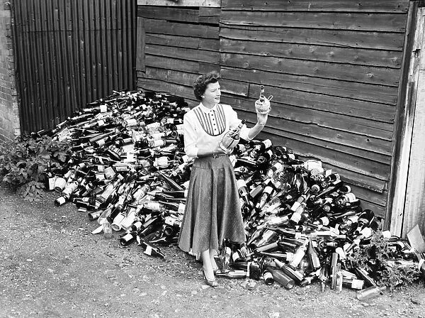 Woman seen here inspecting wine bottles. 1957 A17