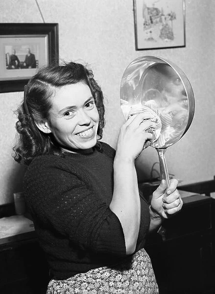 Woman seen in the kitchen drying a frying pan. Circa February 1952