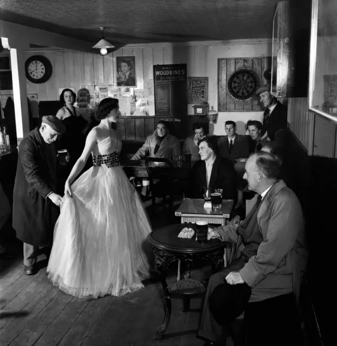Framed Print : Woman showing off a long white dress to a room full of local men during a fashion Show in Framed Print : Woman showing off a long white dress to a room full of local men during a fashion Show in