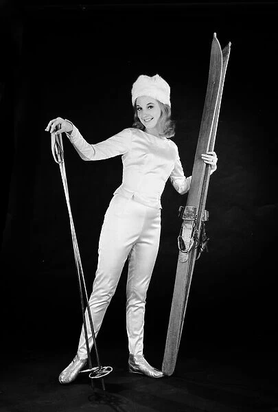 Woman in ski outfit with skis and poles. Circa 1964