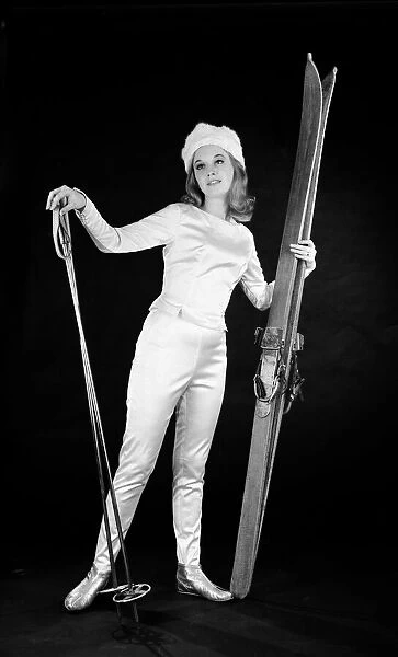 Woman in ski outfit with skis and poles. Circa 1964
