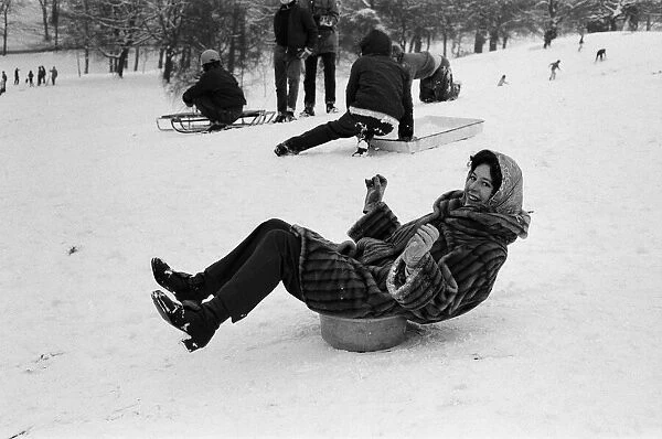 A woman sledging on a washing up bowl in Greenwich Park, London, 27th December 1970