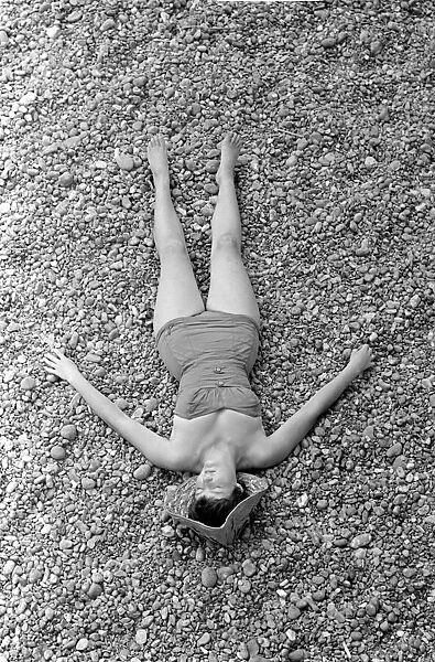 A woman sunbathing on the pebble beach at Brighton July 1958