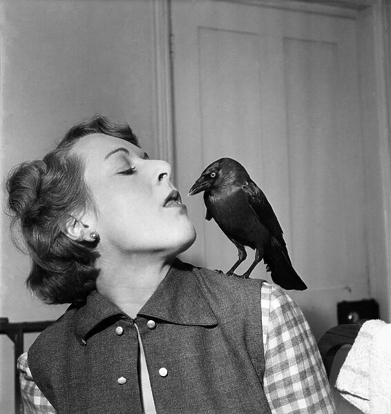 Woman talking to a bird perched on her shoulder. November 1952 C5808-004