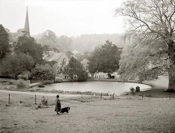 A woman walking her border collie dog in the countryside Lake church trees field