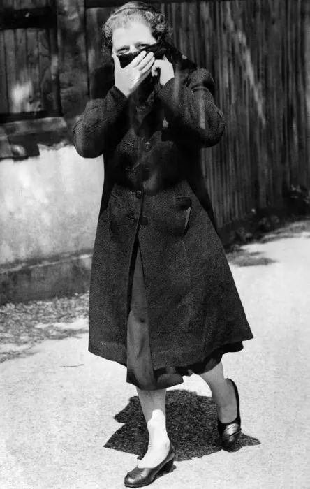 Framed Print : Woman walking down the street wearing a long over coat and turning up the collar to cover