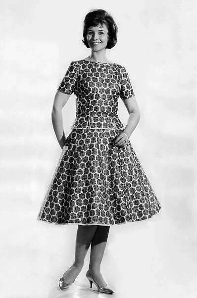 Woman wearing a patterned knee length flared dress. May 1962 P011065