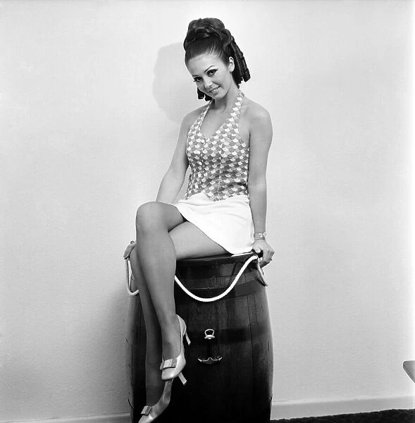 Woman wearing a patterned top and short skirt posing with a barrel