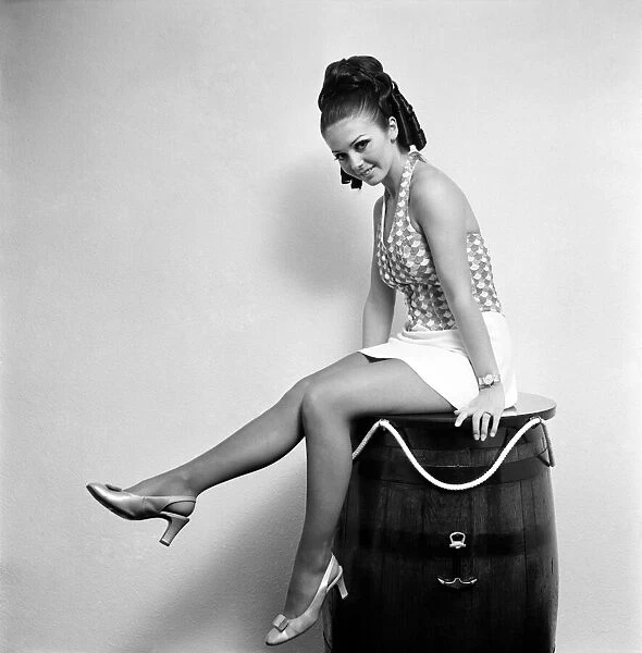 Woman wearing a patterned top and short skirt posing with a barrel