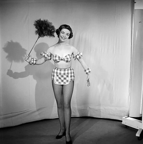 Woman wearing plaid bra and short skirt holding duster. 1959